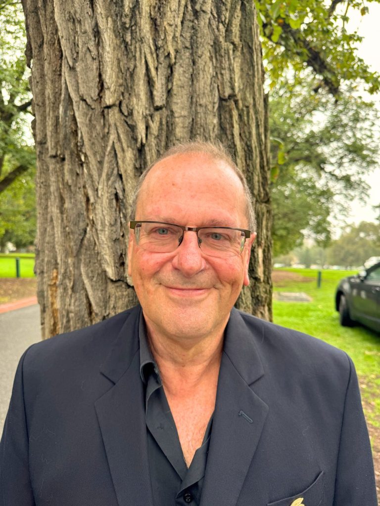 Ian Harris of Redback Health Services, standing in front of tree outside MCG, Melbourne